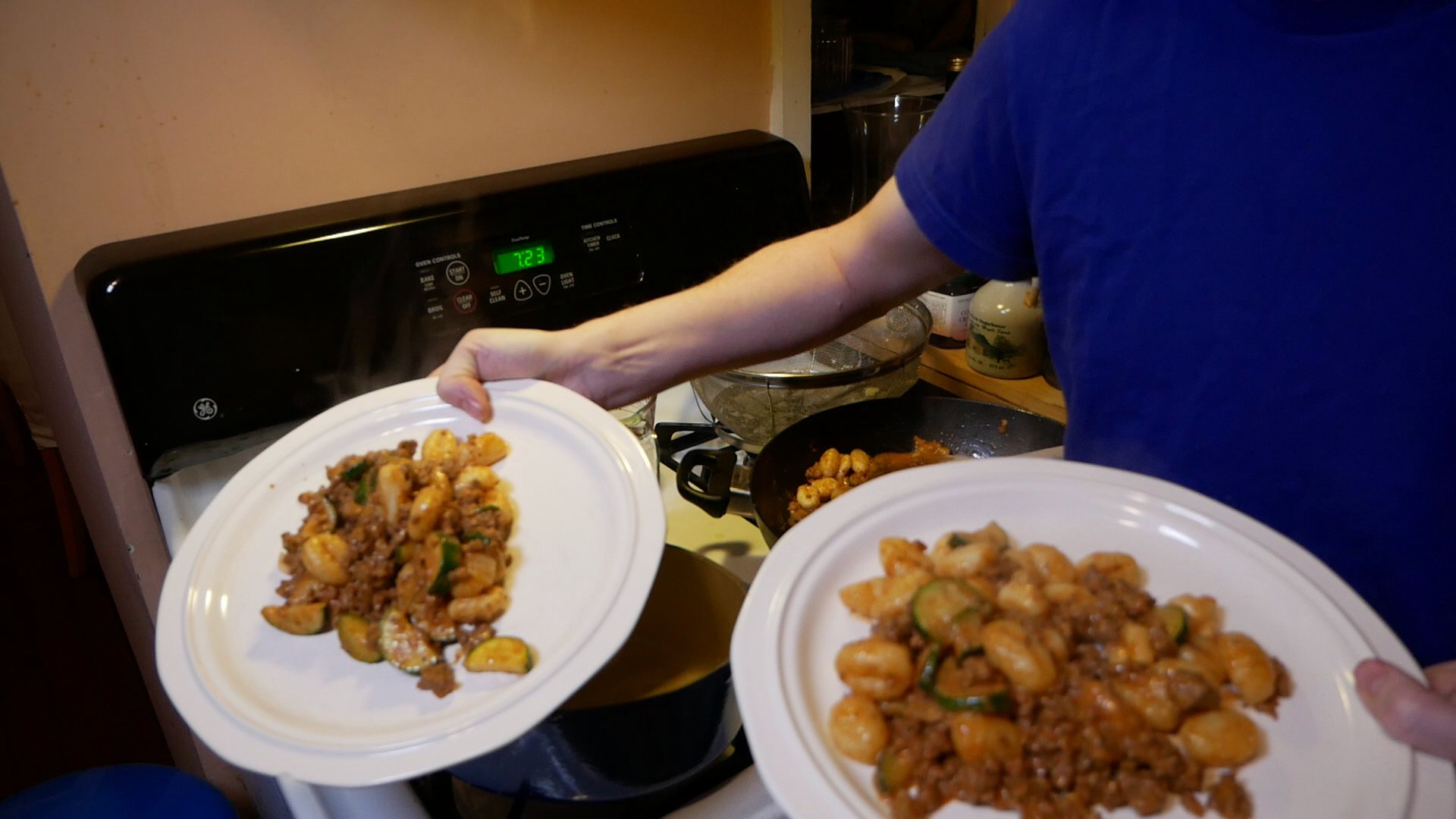 Two plates of prepared food against a backdrop of a stove with numerous pots on it