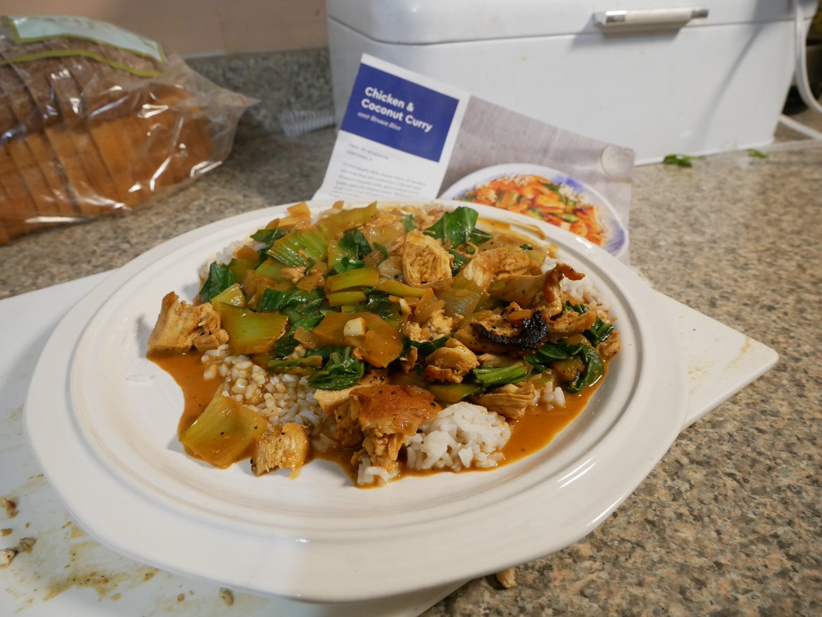 Plate of Chicken and Coconut Curry, with Blue Apron recipe pictured behind.